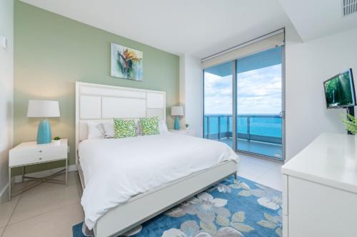 a bedroom with a white bed and a large window at Churchill Suites Monte Carlo Miami Beach in Miami Beach