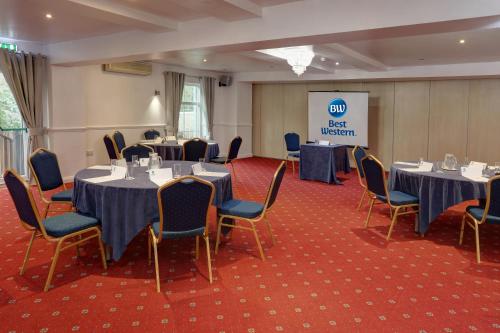 a conference room with tables and chairs and a screen at Best Western Claydon Hotel in Ipswich