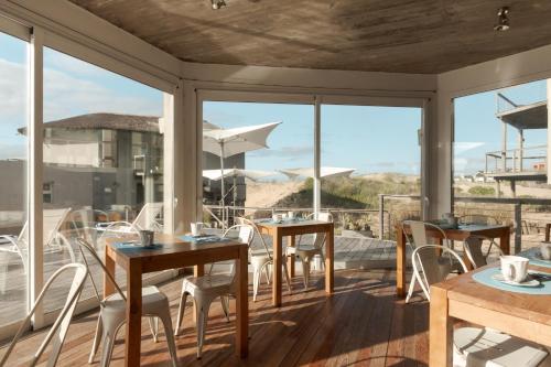 a patio with tables and chairs and a view of the ocean at MarAdentro Apart Hotel & Suites in Punta Del Diablo
