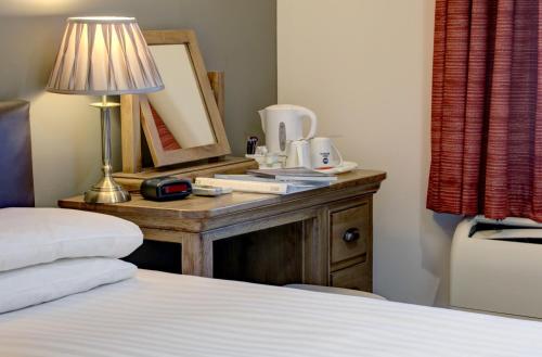 a bedroom with a bed and a table with a lamp at Best Western Claydon Hotel in Ipswich