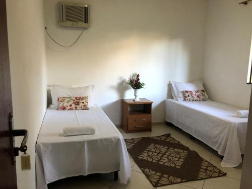 a room with two beds and a table and a chair at Maras Flats in Trancoso