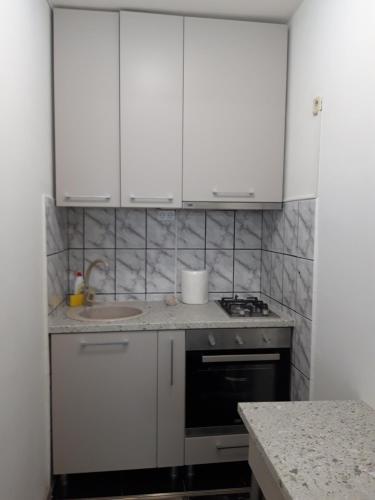 een keuken met witte kasten en een spoelbak bij Apartament Elena in Sinaia