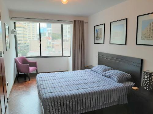 une chambre avec un lit, une chaise et une fenêtre dans l'établissement Miraflores Kennedy's Park Apartment, à Lima