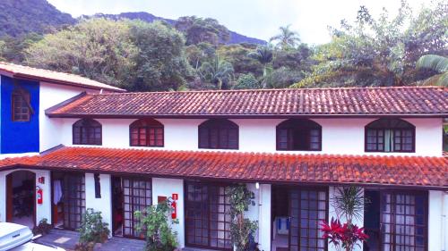 a white house with a red roof and trees at Pousada Em Busca do Sol in Trindade