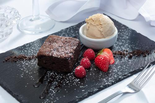 a black plate with chocolate cake and ice cream and strawberries at Best Western Claydon Hotel in Ipswich