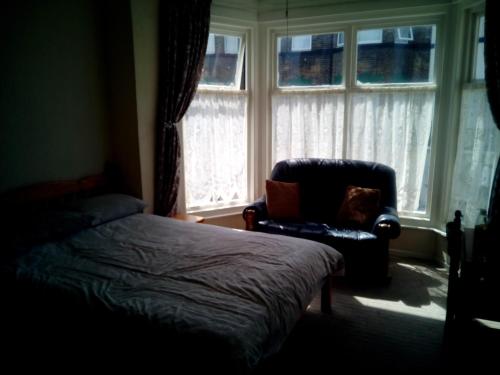 a bedroom with a bed and a chair and a window at 2 berth first floor flat Apsley 4 in Great Yarmouth