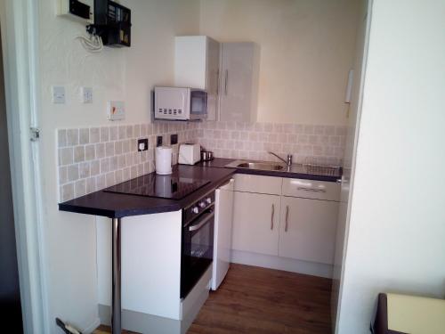 a small kitchen with white cabinets and a sink at 2 berth first floor flat Apsley 4 in Great Yarmouth