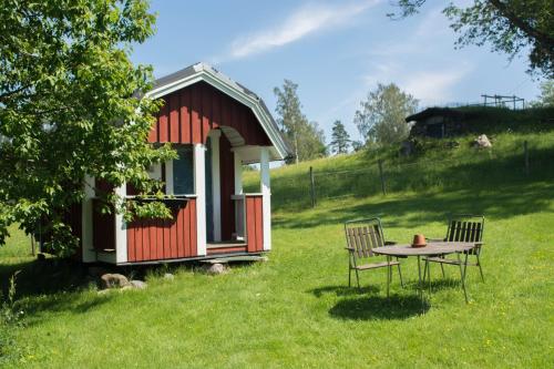 a small red cabin with a table and chairs in the grass at STF Tivedstorp in Tivedstorp