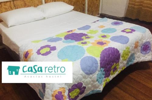 a bed with a colorful quilt on top of it at Casa Retro Acacias Hostel in Acacías