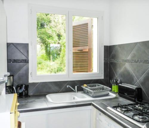 une cuisine avec un évier et une fenêtre dans l'établissement Maison charmante à San-Nicolao avec piscine partagée, à San-Nicolao