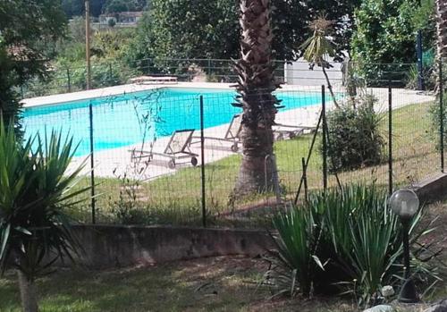 une clôture en face d'une piscine dans l'établissement Maison charmante à San-Nicolao avec piscine partagée, à San-Nicolao