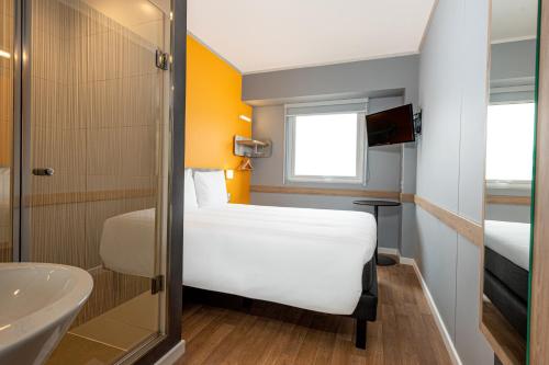 uma pequena casa de banho com uma cama branca e um lavatório em ibis budget Lima Miraflores em Lima