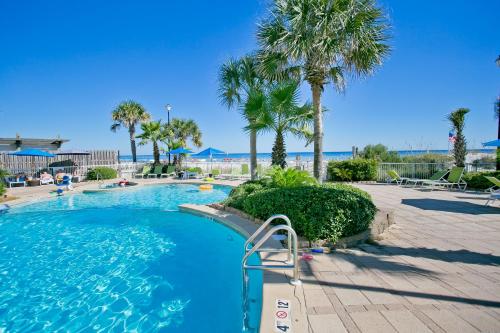 a swimming pool with palm trees in a resort at Holiday Inn Express Orange Beach - On The Beach by IHG in Orange Beach
