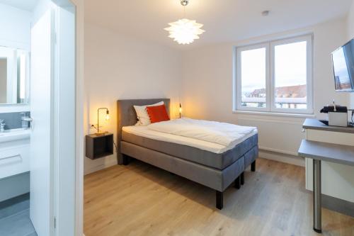 a bedroom with a bed and a desk and a window at STAY@MA Boardinghouse Mannheim in Mannheim
