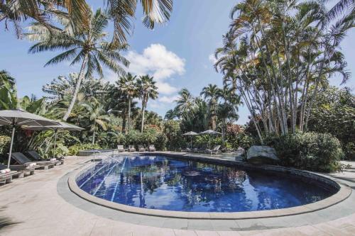 einen Pool in einem Resort mit Palmen in der Unterkunft Pacific Resort Rarotonga in Rarotonga