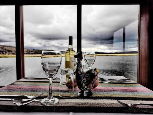 een tafel met twee glazen en een fles wijn bij Titicaca Lodge Peru in Puno