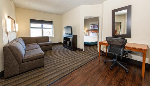 a living room with a couch and a desk and a bed at Hyatt House Chicago Schaumburg in Schaumburg