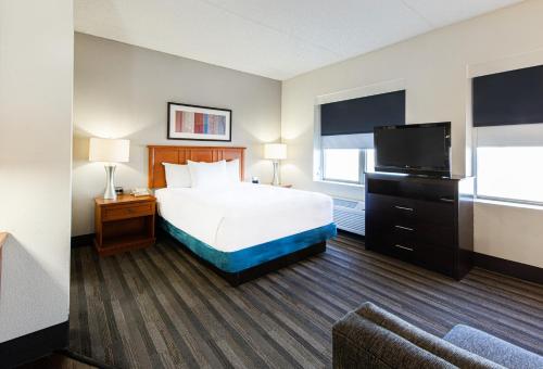a hotel room with a bed and a flat screen tv at Hyatt House Chicago Schaumburg in Schaumburg