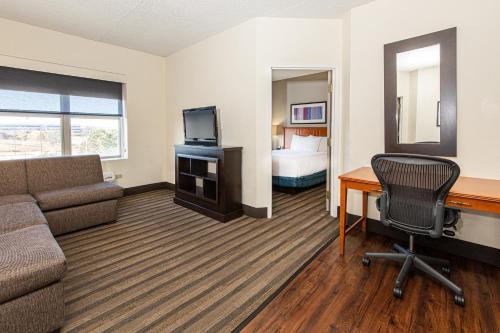 a hotel room with a couch and a desk and a bed at Hyatt House Chicago Schaumburg in Schaumburg