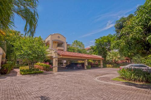 a house with a car parked in front of a driveway at Ocean View Condo in Los Sueños in Herradura
