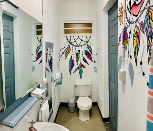 a bathroom with a toilet with colorful feathers on the wall at Hotel y Arte Antigua by Amazing Guatemala Travel in Antigua Guatemala