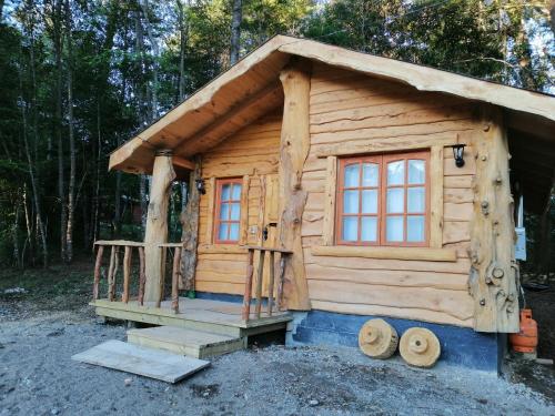 a small log cabin with a porch and windows at Cabañas Los Canelos Pucon, Hermosa Granja de 20 hectaréas a orillas del Río Liucura in Pucón