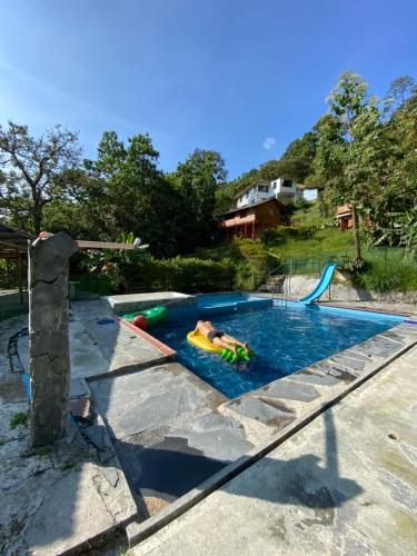 een persoon die zwemt in een zwembad met een zwembad bij Eco Lodge La Juanita in Manizales