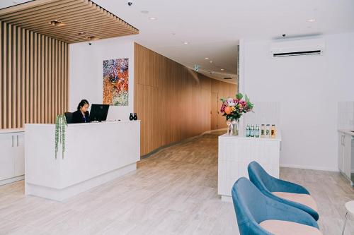 a woman sitting at a reception desk in a lobby at Toms Court Hotel in Adelaide