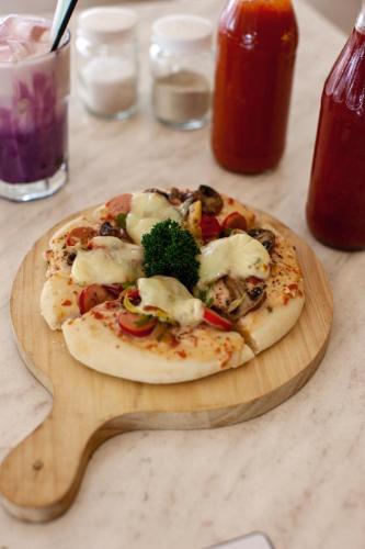 a pizza on a wooden cutting board on a table at Shakti Hotel Bandung in Bandung