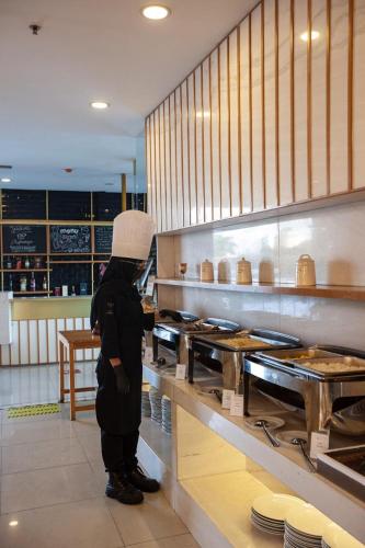 a person wearing a chefs hat standing in a kitchen at Shakti Hotel Bandung in Bandung
