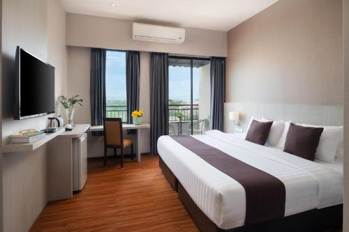 Habitación de hotel con cama y escritorio con TV. en The Pino Hotel Pakchong, en Pak Chong