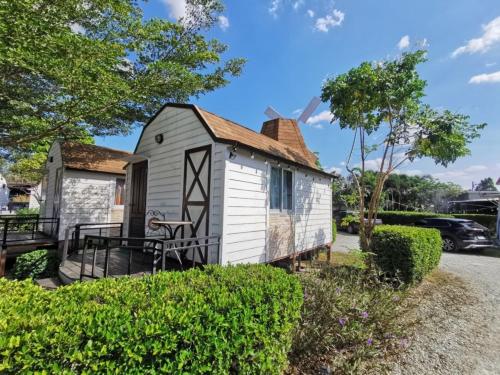 a tiny house with a porch and a patio at De Coco House in Si Racha
