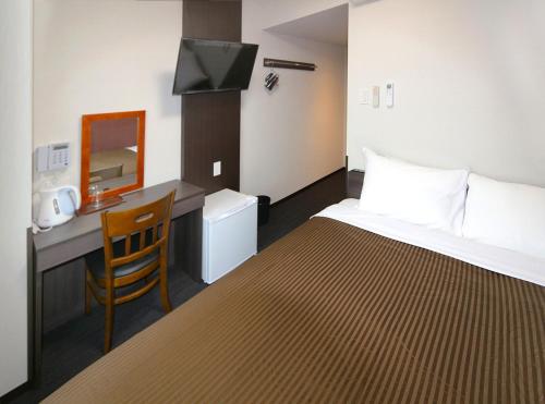 a hotel room with a bed and a desk at Hotel Trend Suzuka in Suzuka