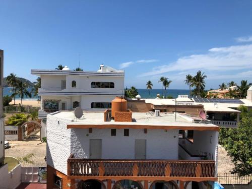 a white house on the beach with the ocean behind it at Bungalows Flamingos in Rincon de Guayabitos