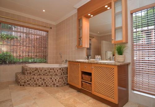 een badkamer met een bad, een wastafel en een bad bij Upmarket Villa with pool & lush garden in Pretoria