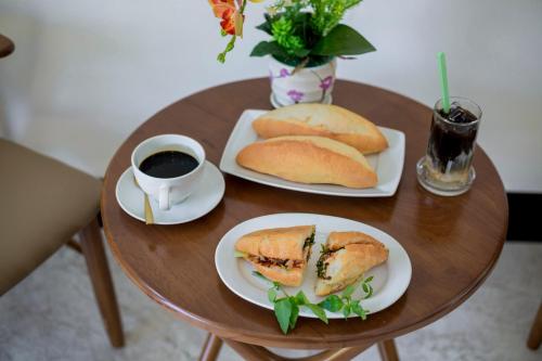 a table with two plates of sandwiches and a cup of coffee at Dawn Villa Homestay Hội An in Hoi An