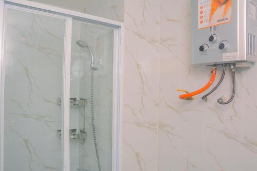 a shower with a glass door in a bathroom at Grand Kamala Lagoon Studio Apartment with Modern Interior By Travelio in Pekayon Satu