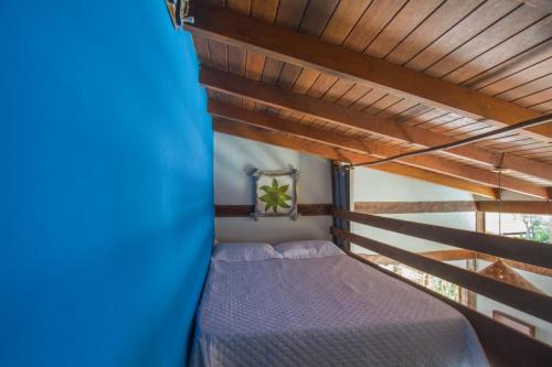 a bed in a room with a wooden ceiling at Zeisa House in Maresias