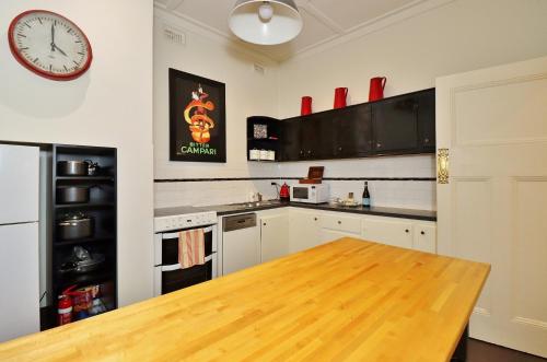 a kitchen with a wooden table and a clock on the wall at McKenzie House in Healesville