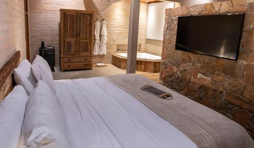 a bedroom with a large bed with a stone wall at Canto do Irere - Boutique Hotel in Atibaia