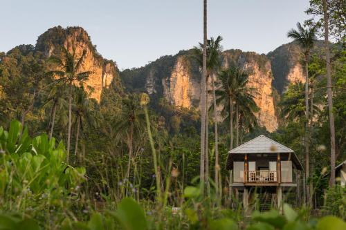 a small house in front of a mountain with palm trees at Tinidee Hideaway Tonsai Beach Krabi - SHA Extra Plus in Tonsai Beach