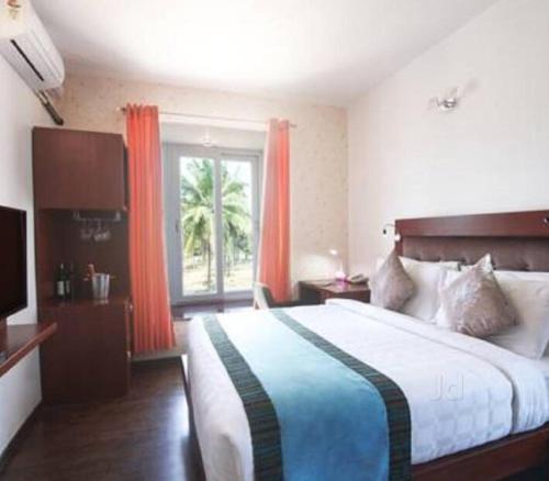 1 dormitorio con 1 cama y una ventana con cortinas de color naranja en Avi Fortune Suites - Near Bangalore International Airport, en Bangalore