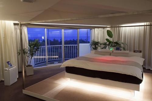 1 dormitorio con 1 cama grande y balcón en Hotel Oarai Seven Seas(Adult Only), en Oarai