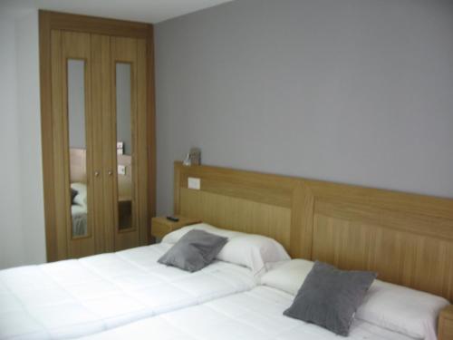a bedroom with two white beds and a mirror at Hostal Libertad in Gijón