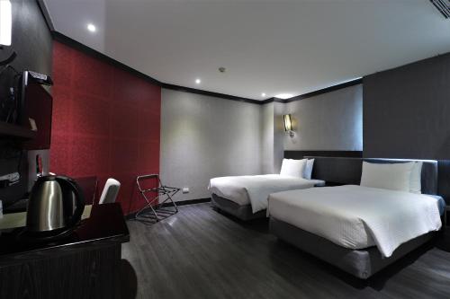 a hotel room with two beds and a television at J-HOTEL in Kaohsiung