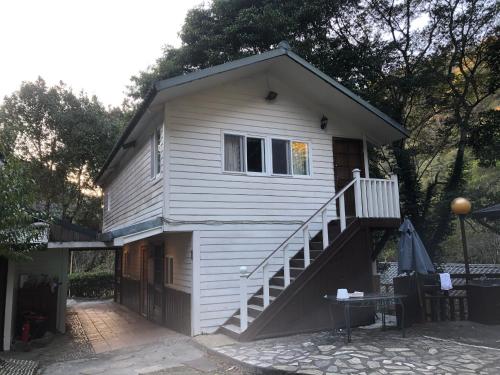 a white house with a staircase in front of it at 溪景生態農莊 桃園市民宿037號 in Hualing