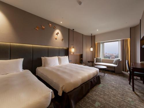 a hotel room with two beds and a desk at The Howard Prince Hotel Taichung in Taichung