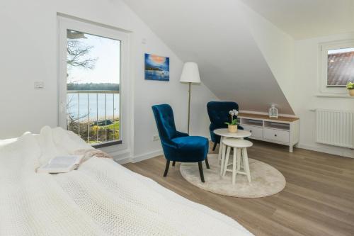 a bedroom with a bed and two chairs and a table at 5 Sterne Ferienhaus direkt am See mit Sauna-Kamin-Garten in Krakow am See