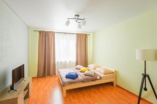 um quarto com uma cama e uma televisão em Apartments Abajur on Pichugina street 6 em Kurgan