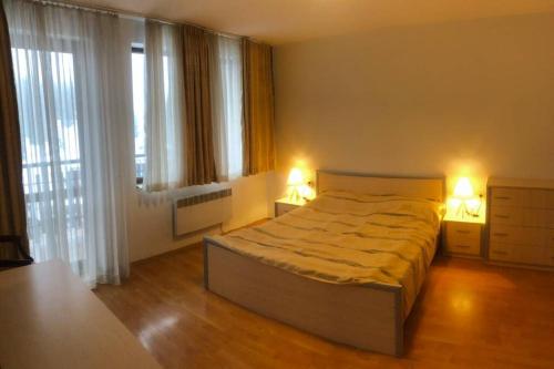 a bedroom with a large bed and two lamps on tables at Апартамент Пампорово Палас - Pamporovo Palace in Pamporovo